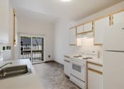 Thumbnail 13 of 36 - A kitchen with white appliances and a window overlooking a balcony.