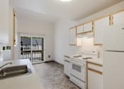 Thumbnail 11 of 36 - A kitchen with white appliances and a window overlooking a balcony.
