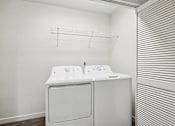 Thumbnail 18 of 46 - A white washing machine and dryer in a small laundry room.