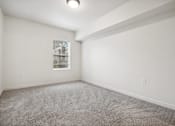 Thumbnail 19 of 46 - A room with a carpeted floor and a window showing a building outside.