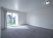 Thumbnail 30 of 34 - A room with a carpeted floor and a sliding glass door leading to a backyard.