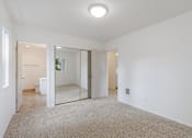 Thumbnail 17 of 36 - A spacious room with a carpeted floor and a large mirror on the wall.