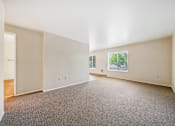 Thumbnail 16 of 35 - A large empty room with a carpeted floor and a window.