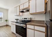Thumbnail 50 of 74 - A kitchen with white cabinets and a black stove top oven.
