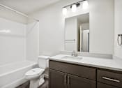 Thumbnail 23 of 46 - A white toilet sits in a bathroom next to a sink and a mirror.