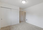 Thumbnail 19 of 36 - A white room with a carpeted floor and a door on the left.