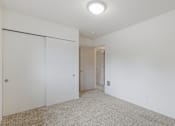Thumbnail 17 of 36 - A white room with a carpeted floor and a sliding door.