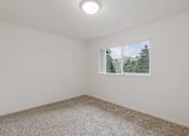 Thumbnail 18 of 36 - A room with a carpeted floor and a window showing a view of a house and trees.
