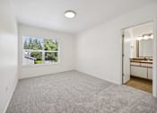 Thumbnail 52 of 74 - A room with a carpeted floor and a window showing a view of trees and a house.
