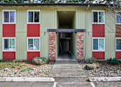 Thumbnail 4 of 44 - A building with a red and green exterior and a covered walkway leading to the entrance.