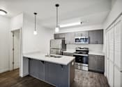Thumbnail 7 of 46 - A modern kitchen with a white countertop and stainless steel appliances.