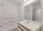 Thumbnail 21 of 36 - A white bathroom with a sink, mirror, and bathtub.