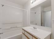 Thumbnail 19 of 36 - A white bathroom with a sink, mirror, and bathtub.