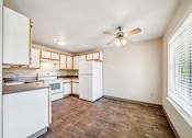 Thumbnail 18 of 25 - A kitchen with white cabinets and a wooden floor.