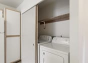 Thumbnail 22 of 36 - A white washing machine and dryer in a small laundry room.