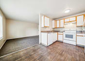 Thumbnail 21 of 35 - A kitchen with white cabinets and a wooden floor.