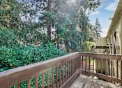 Thumbnail 31 of 44 - A wooden deck with a railing and trees in the background.