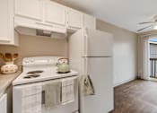 Thumbnail 27 of 31 - A kitchen with a white stove and a white refrigerator with a white wall and a white ceiling.