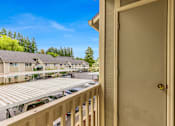 Thumbnail 22 of 36 - A view from a balcony of a building with a car parked in the driveway.