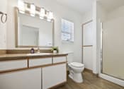 Thumbnail 56 of 74 - A bathroom with a toilet, sink, mirror, and wooden floors.