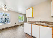 Thumbnail 23 of 35 - A kitchen with white cabinets and a window overlooking a house.