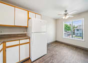 Thumbnail 14 of 25 - A white refrigerator in a kitchen with wooden cabinets.
