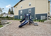 Thumbnail 30 of 46 - A playground with a blue slide in front of a building.