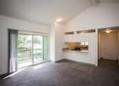 Thumbnail 30 of 40 - A spacious room with a kitchen area and a sliding glass door leading to a balcony.