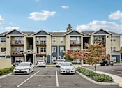 Thumbnail 2 of 46 - A row of townhouses with cars parked in front.