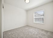 Thumbnail 26 of 74 - A room with a carpeted floor and a window with blinds.