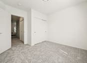 Thumbnail 27 of 74 - A room with white walls and carpeted floor with a doorway leading to another room.