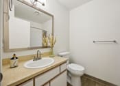 Thumbnail 28 of 74 - A bathroom with a toilet, sink, mirror, and towel rack.