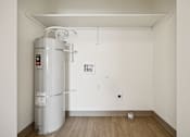 Thumbnail 62 of 74 - A water heater is installed in a room with white walls and wooden flooring.