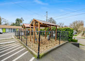 Thumbnail 10 of 31 - A playground with a wooden structure and a black fence.