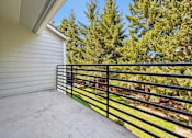 Thumbnail 32 of 74 - A balcony with a black railing overlooking a green tree.