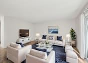 Thumbnail 12 of 44 - A living room with a white couch and a blue rug.
