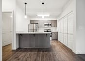 Thumbnail 12 of 46 - A modern kitchen with a wooden floor and white walls.