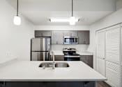 Thumbnail 14 of 46 - A modern kitchen with a stainless steel refrigerator, microwave, and oven.