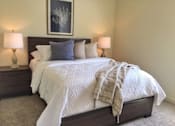 Thumbnail 38 of 46 - A bed with a white comforter and a brown blanket is in the center of the image.
