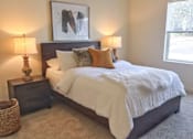 Thumbnail 39 of 46 - A bedroom with a bed, two lamps, and a painting on the wall.
