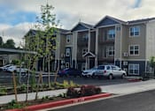 Thumbnail 4 of 46 - Apartment complex with a parking lot in front.