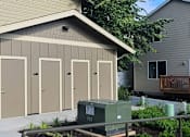 Thumbnail 41 of 46 - A small building with four doors is situated in front of a house.