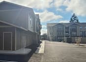 Thumbnail 42 of 46 - A parking lot with a building in the background.