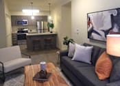 Thumbnail 36 of 46 - A modern living room with a grey couch and a wooden coffee table.