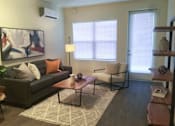Thumbnail 35 of 46 - A living room with a grey couch, a coffee table, and a painting on the wall.