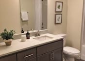 Thumbnail 43 of 46 - A bathroom with a white toilet and a sink with a mirror above it.