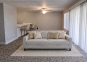 Thumbnail 4 of 17 - A living room with a couch, a rug, and a table with chairs.
