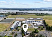 Thumbnail 38 of 50 - An aerial view of a large industrial area with a lake and mountains in the distance.