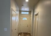 Thumbnail 6 of 18 - A hallway with a wooden floor and white walls.