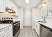 Thumbnail 25 of 40 - A modern kitchen with white cabinets and stainless steel appliances.